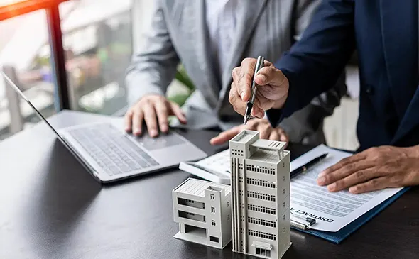 Real estate agent working in an office, reviewing property listings and assisting clients.