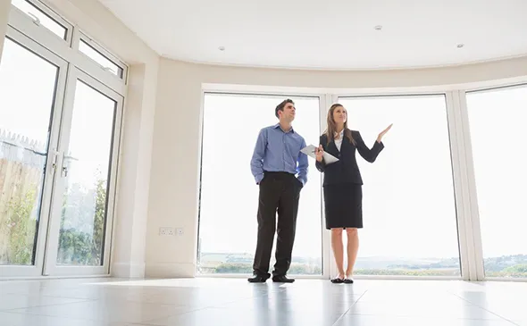 A man and woman stand in an empty room, representing Commercial Downsizing Real Estate opportunities.