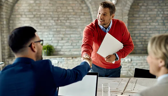 Two men shake hands in an office, discussing a potential commercial property investment opportunity.