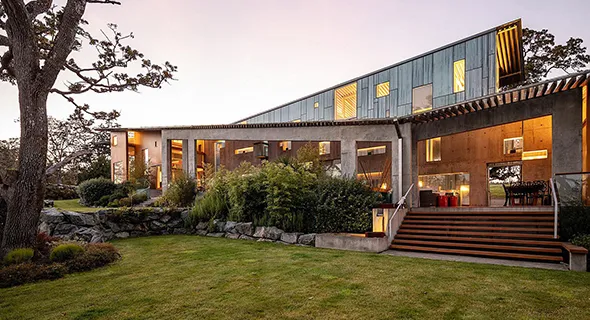 A sleek modern home with expansive lawn and trees, part of a luxury property development.