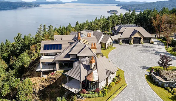 Aerial view of a large home with a serene lake in the background, showcasing a prime real estate opportunity.